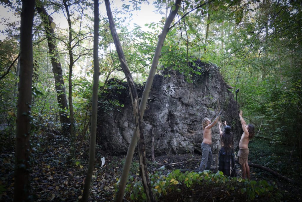 A large uprooted tree, rising from the ground like a backdrop holding ancient secrets. Fine art nude