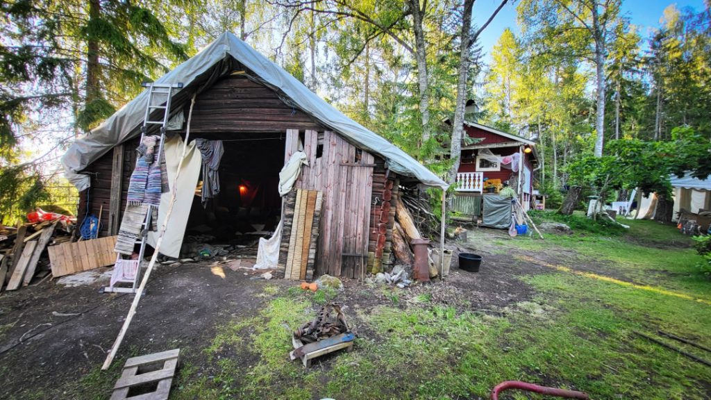 group of naked people gathered around a fire in a forest clearing, sharing laughter, silence, and raw conversation — a moment of deep presence, honesty, and human connection at Rotum, a space where nothing is forced, and nothing needs to be explained.